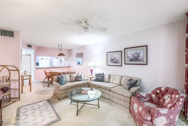 living area with visible vents, a ceiling fan, and carpet