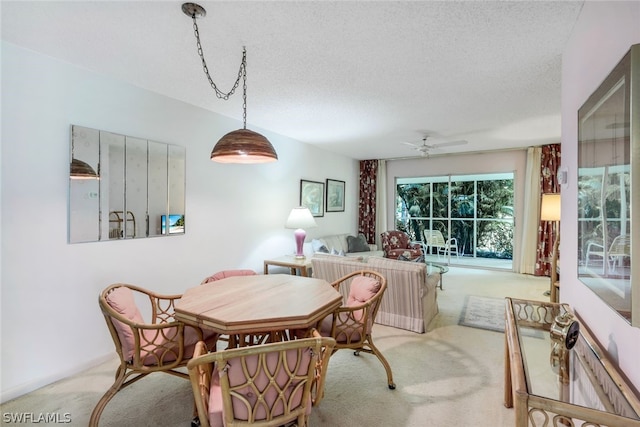 carpeted dining area featuring a textured ceiling and ceiling fan