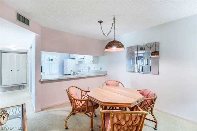 dining room with baseboards, light colored carpet, a textured ceiling, and visible vents