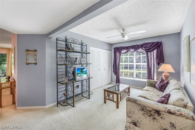 living room featuring a textured ceiling, ceiling fan, carpet flooring, and beam ceiling