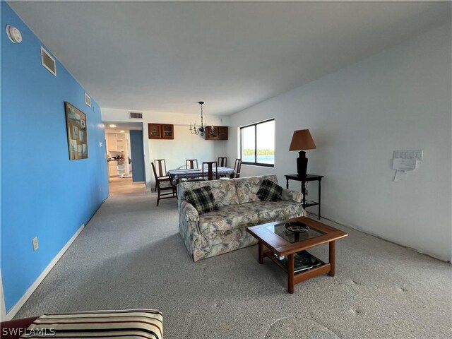 carpeted living room with a chandelier