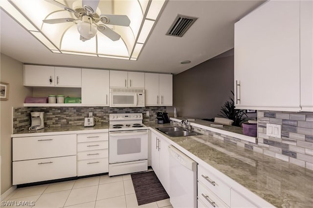 kitchen with tasteful backsplash, white appliances, sink, white cabinets, and light tile patterned flooring