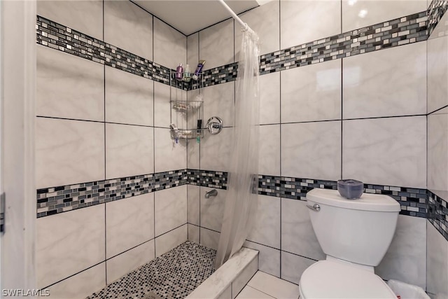 bathroom featuring a shower with shower curtain, toilet, and tile walls