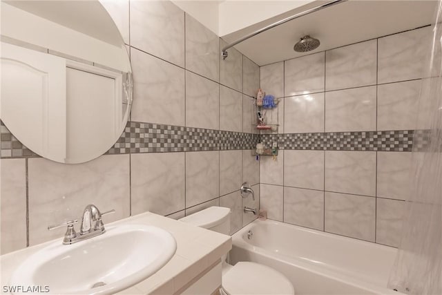 full bathroom featuring sink, tiled shower / bath, tile walls, and toilet