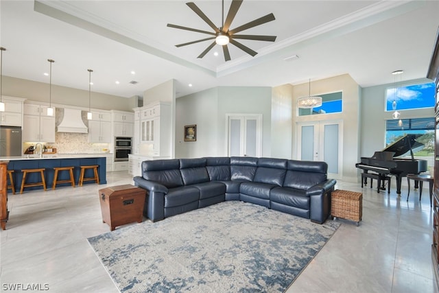 living room with french doors, sink, a towering ceiling, ceiling fan with notable chandelier, and ornamental molding