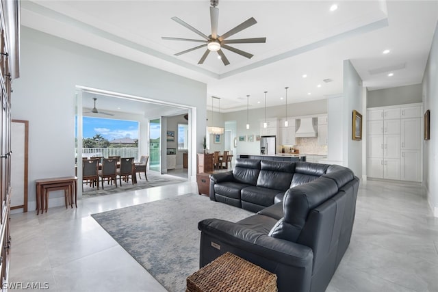 living room featuring a tray ceiling, ceiling fan, and crown molding