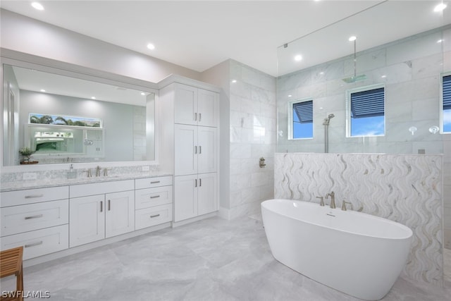 bathroom with vanity, shower with separate bathtub, and tile walls