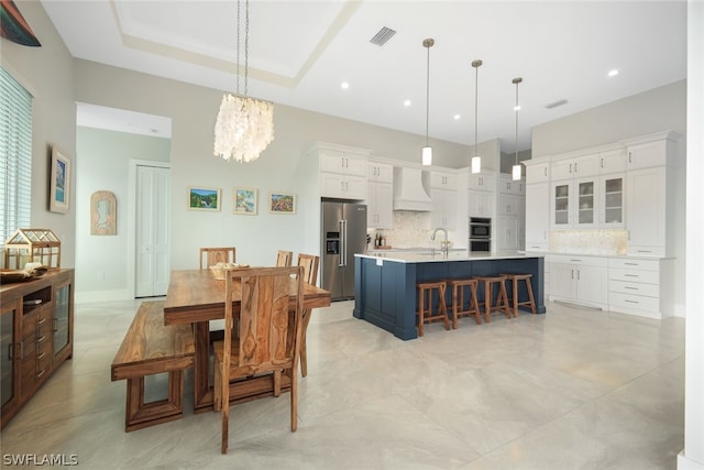 dining space with a notable chandelier, a raised ceiling, and sink