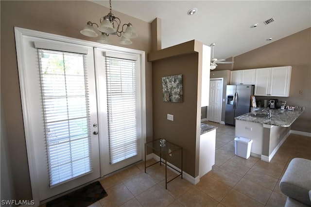 kitchen with stainless steel fridge, white cabinets, decorative light fixtures, vaulted ceiling, and kitchen peninsula