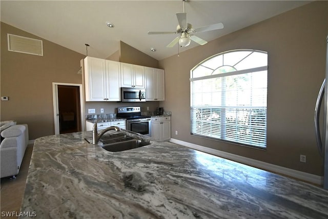 kitchen featuring sink, stainless steel appliances, dark stone counters, and white cabinets