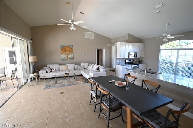 tiled dining room featuring ceiling fan, high vaulted ceiling, and sink