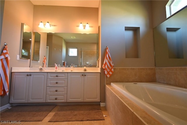 bathroom with tile patterned flooring, vanity, and tiled tub