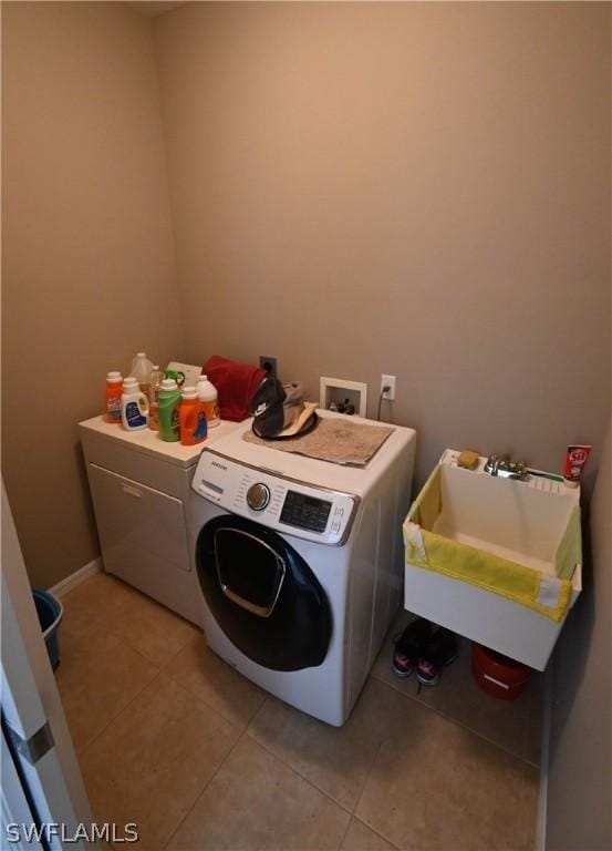 clothes washing area featuring sink, light tile patterned floors, and independent washer and dryer