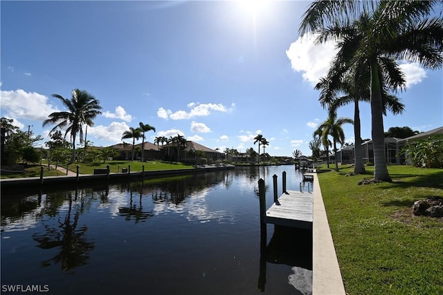 view of dock with a water view and a yard