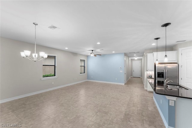 kitchen with pendant lighting, sink, stainless steel fridge, and white cabinets