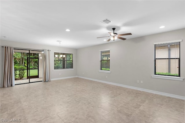 spare room featuring ceiling fan with notable chandelier