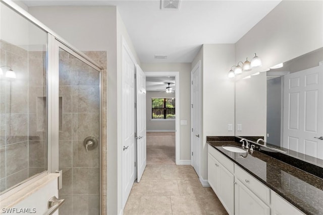 bathroom with ceiling fan, vanity, a shower with shower door, and tile patterned flooring