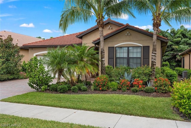 mediterranean / spanish-style house featuring a garage and a front lawn