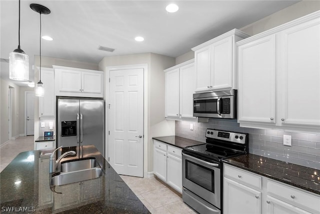 kitchen featuring sink, white cabinetry, hanging light fixtures, dark stone counters, and stainless steel appliances