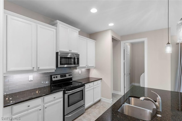 kitchen with sink, hanging light fixtures, dark stone counters, stainless steel appliances, and white cabinets