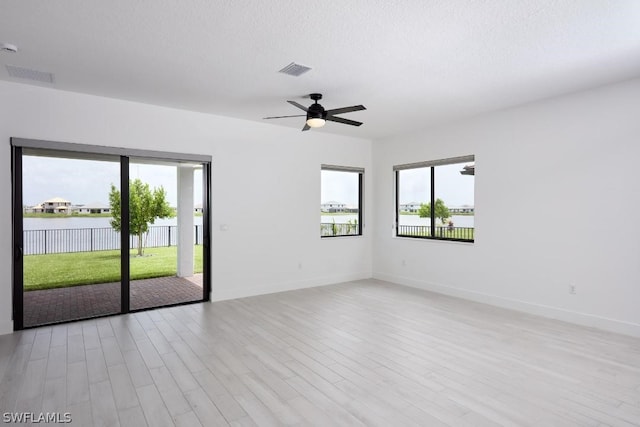 empty room with ceiling fan, a textured ceiling, and light hardwood / wood-style flooring