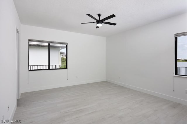 unfurnished room featuring a textured ceiling, light wood-type flooring, a wealth of natural light, and ceiling fan