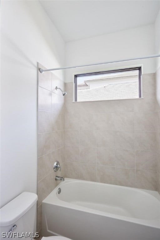 bathroom featuring tiled shower / bath, toilet, and plenty of natural light