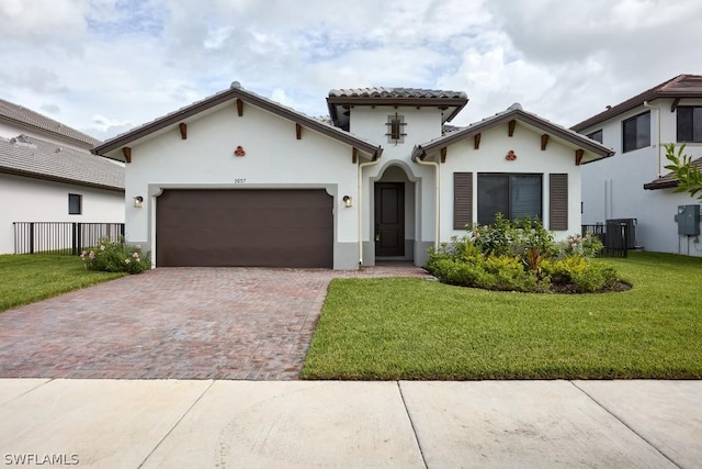 mediterranean / spanish house with central AC unit, a garage, and a front lawn