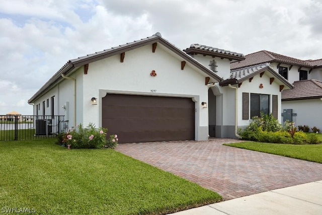 mediterranean / spanish house featuring a front lawn, central AC unit, and a garage