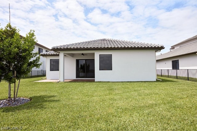 rear view of property featuring a yard and ceiling fan