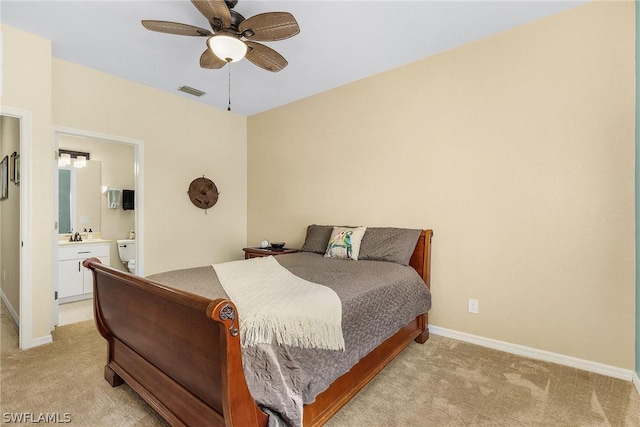 bedroom with ensuite bathroom, ceiling fan, and light carpet