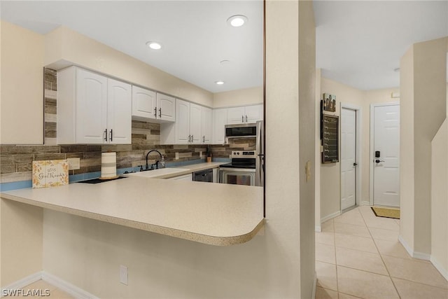 kitchen featuring kitchen peninsula, appliances with stainless steel finishes, tasteful backsplash, sink, and white cabinets