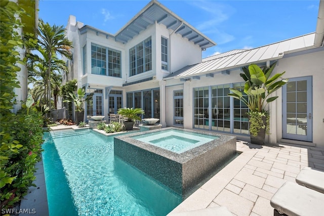 rear view of property featuring a pool with hot tub and a patio area