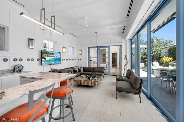 interior space featuring white cabinetry, hanging light fixtures, a kitchen breakfast bar, and light stone countertops