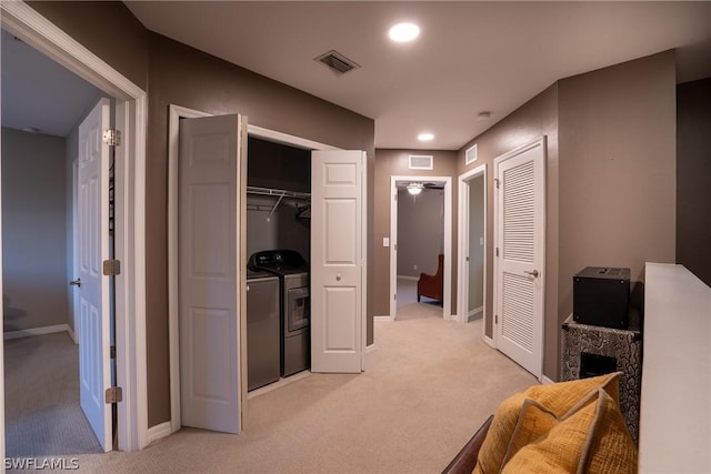 hallway with washer and clothes dryer and light colored carpet