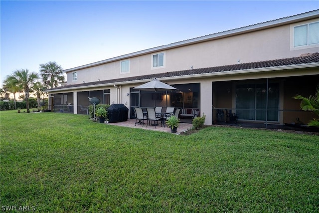 rear view of property with a lawn, a sunroom, and a patio