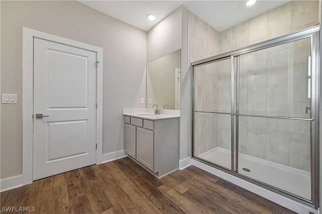 bathroom with recessed lighting, a shower stall, vanity, wood finished floors, and baseboards