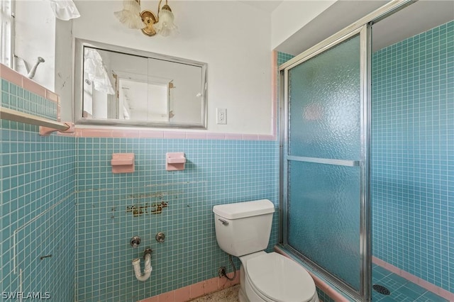 bathroom with a shower with shower door, tile walls, and toilet