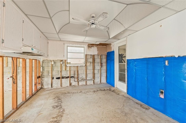 basement featuring a paneled ceiling and ceiling fan