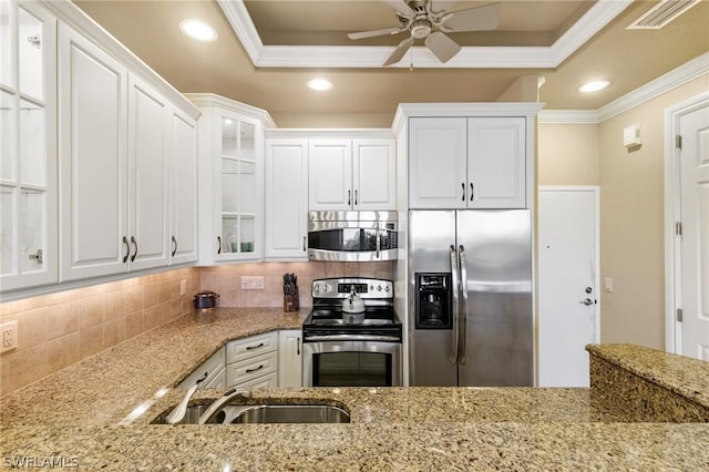 kitchen featuring a raised ceiling, stainless steel appliances, white cabinetry, and tasteful backsplash