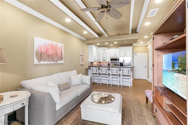 tiled living room with ceiling fan and crown molding