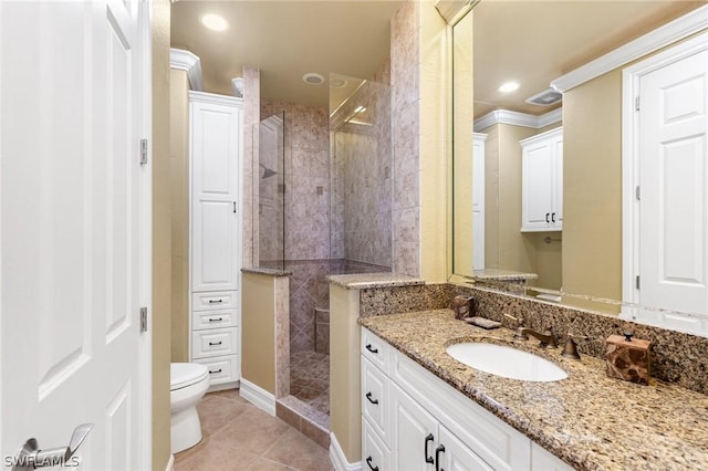 bathroom with tile patterned flooring, toilet, tiled shower, vanity, and ornamental molding