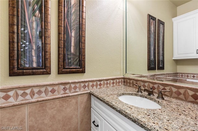 bathroom featuring vanity and tile walls