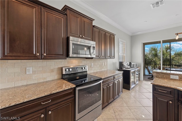 kitchen with light stone counters, light tile patterned flooring, ornamental molding, and appliances with stainless steel finishes