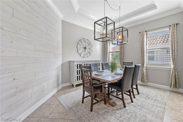 tiled dining space with wood walls, ornamental molding, and a tray ceiling