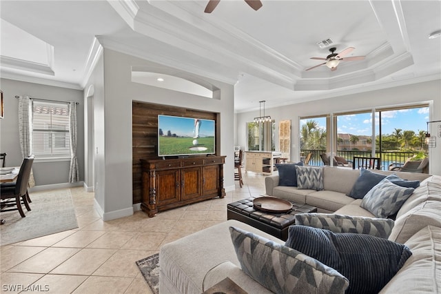 tiled living room featuring ceiling fan with notable chandelier, ornamental molding, and a tray ceiling