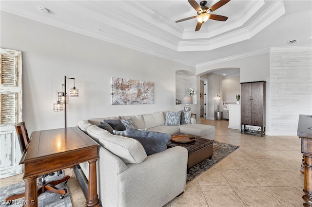 living room with ceiling fan, a raised ceiling, light tile patterned floors, and ornamental molding