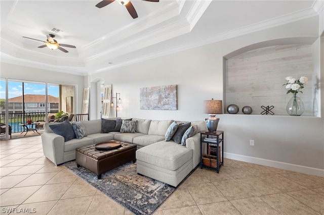 living room featuring a tray ceiling, crown molding, and light tile patterned floors