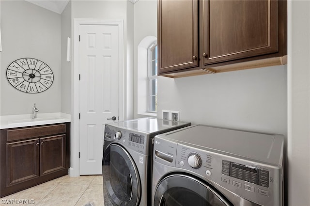 washroom with washing machine and dryer, sink, light tile patterned floors, and cabinets