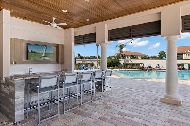 view of swimming pool with ceiling fan, a patio area, and a bar